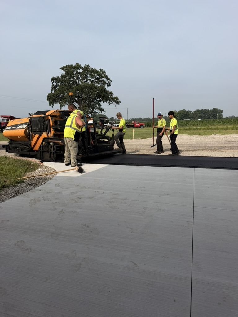 A1-Asphalt crew paving in front of Building 1 — LeeBoy paver and workers in safety vests