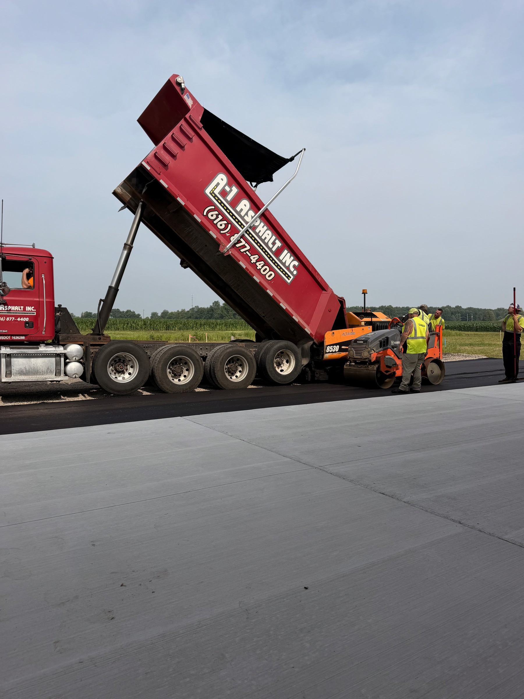 Building 1 at Diamond Garage Condos — fresh black asphalt and three garage bays on asphalt day, July 2026