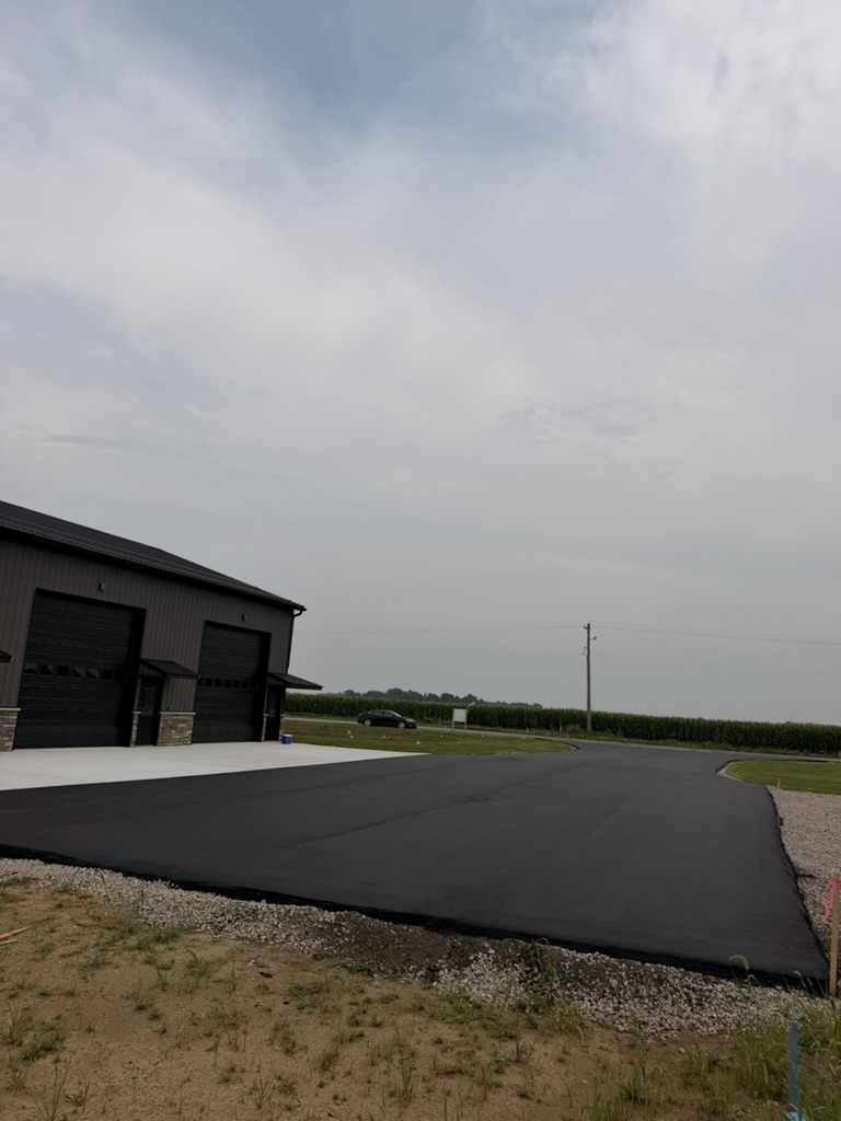 Completed asphalt lot with gray Building 1, black trim, and stone wainscoting on the garage bays