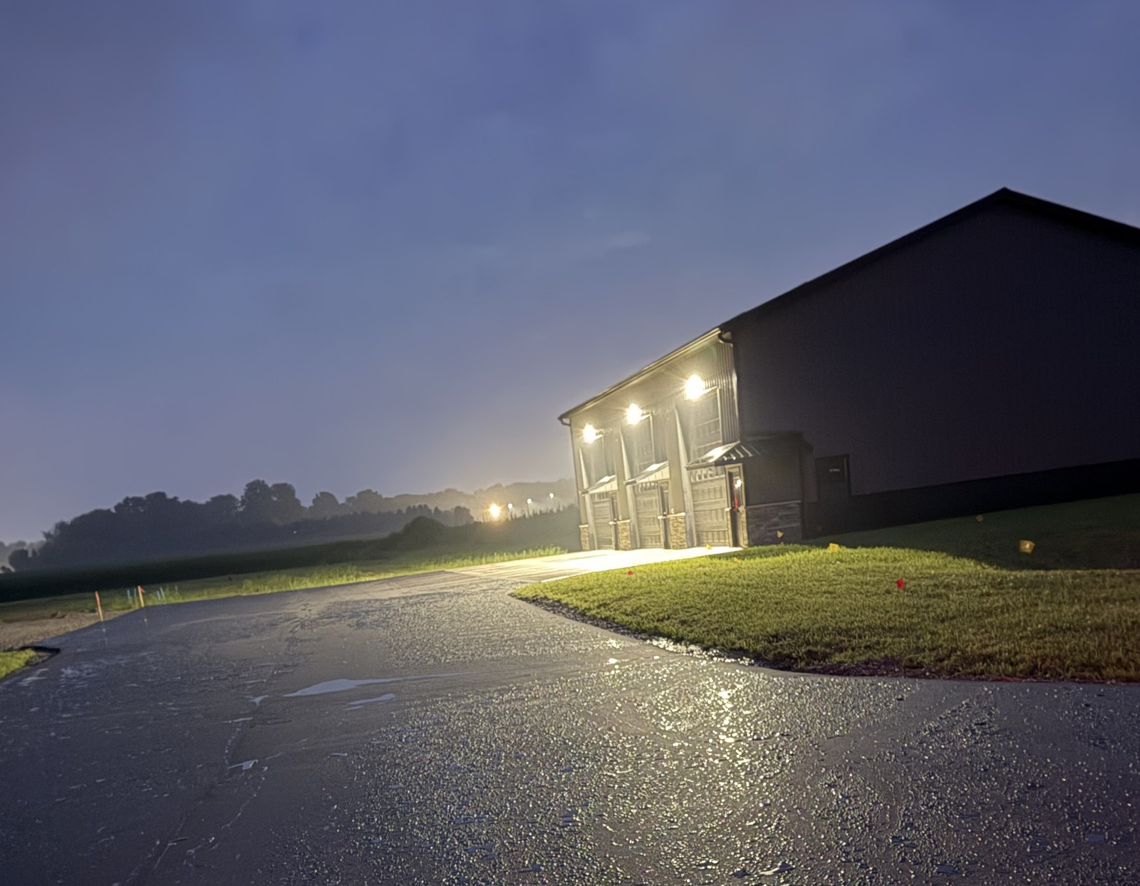 Building 1 at dusk — fresh asphalt reflecting exterior lights on the approach