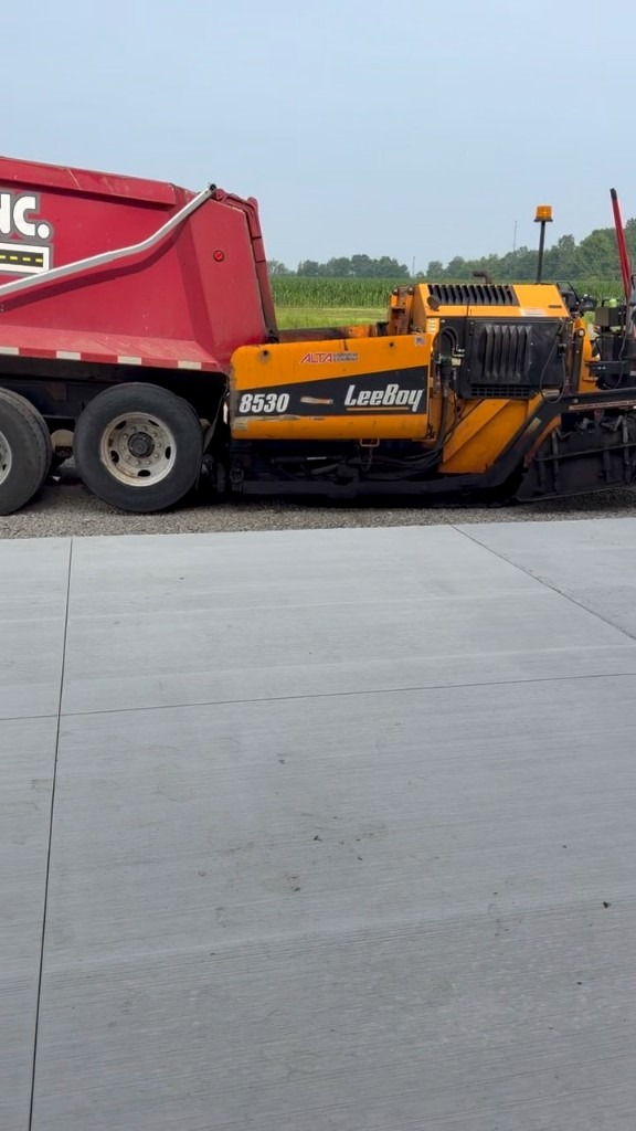LeeBoy 8530 asphalt paver on gravel base with dump truck — A1-Asphalt on site at DGC