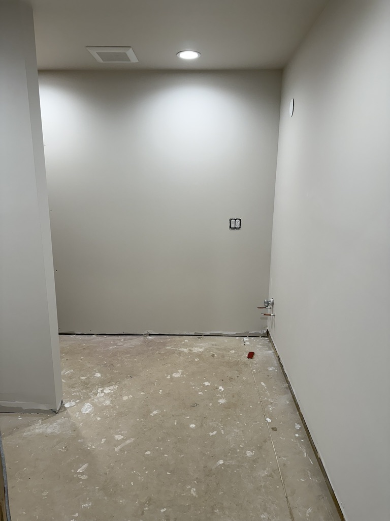 Main-floor bathroom — painted walls, recessed lighting, plumbing stubbed for vanity, concrete floor awaiting tile
