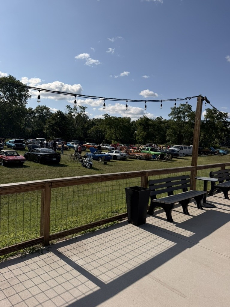 Wide car show field with Corvettes and muscle cars from the Front Street Pizza patio in Niles Michigan