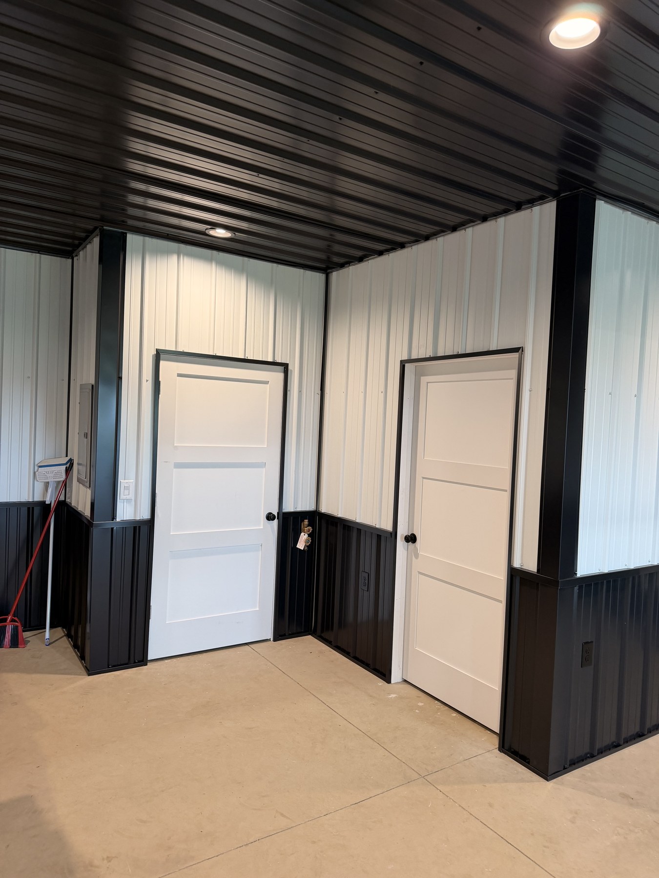 White three-panel interior doors with black hardware against corrugated white and black metal walls
