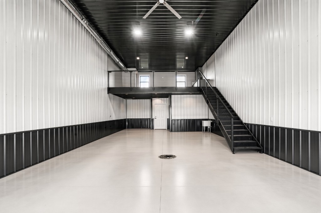 The Lake Bay main bay — epoxy floor, mezzanine with cable rail, black stairs, white under-mezz door
