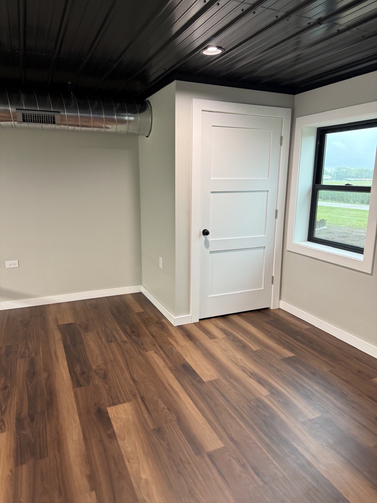 The Lake Bay mezzanine room — wood-look floor, gray walls, black corrugated ceiling, white interior door