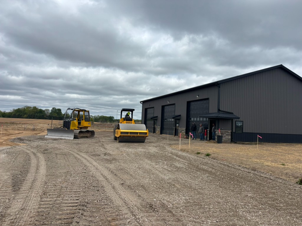 Bulldozer and Sakai roller compacting the lot base in front of the building