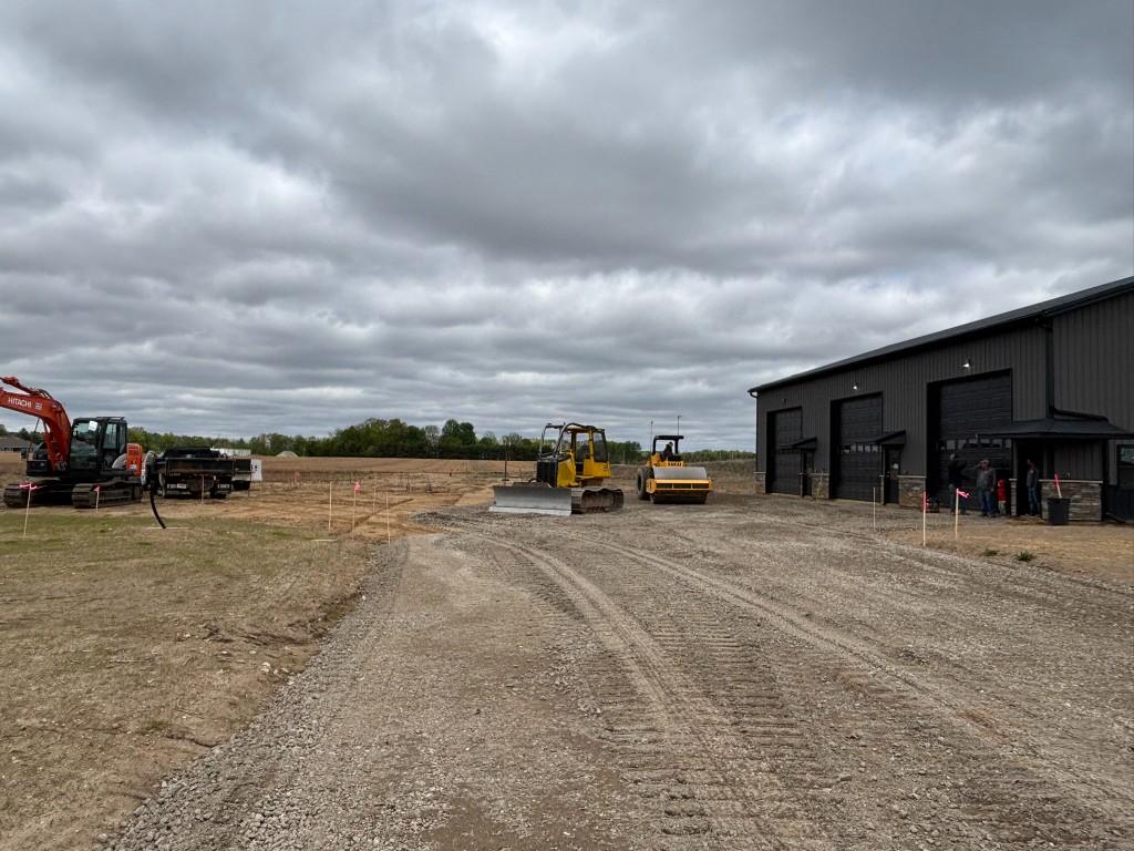 Site overview with roller, bulldozer, and crew near Building 1 entrance