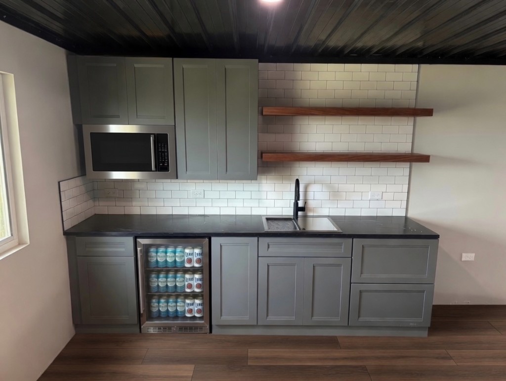 Design vision — completed mezzanine kitchenette with shaker cabinets, beverage cooler, subway tile, and floating wood shelves at Unit 1