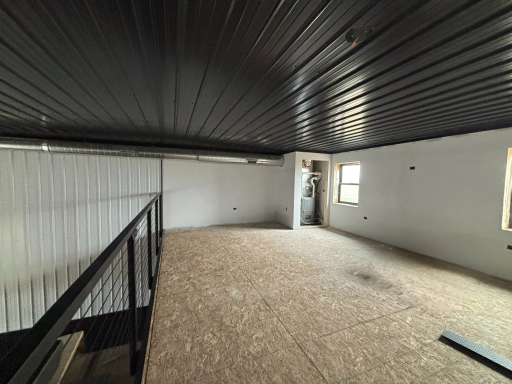 View from top of stairs — cable rail, OSB mezzanine deck, HVAC closet with furnace visible