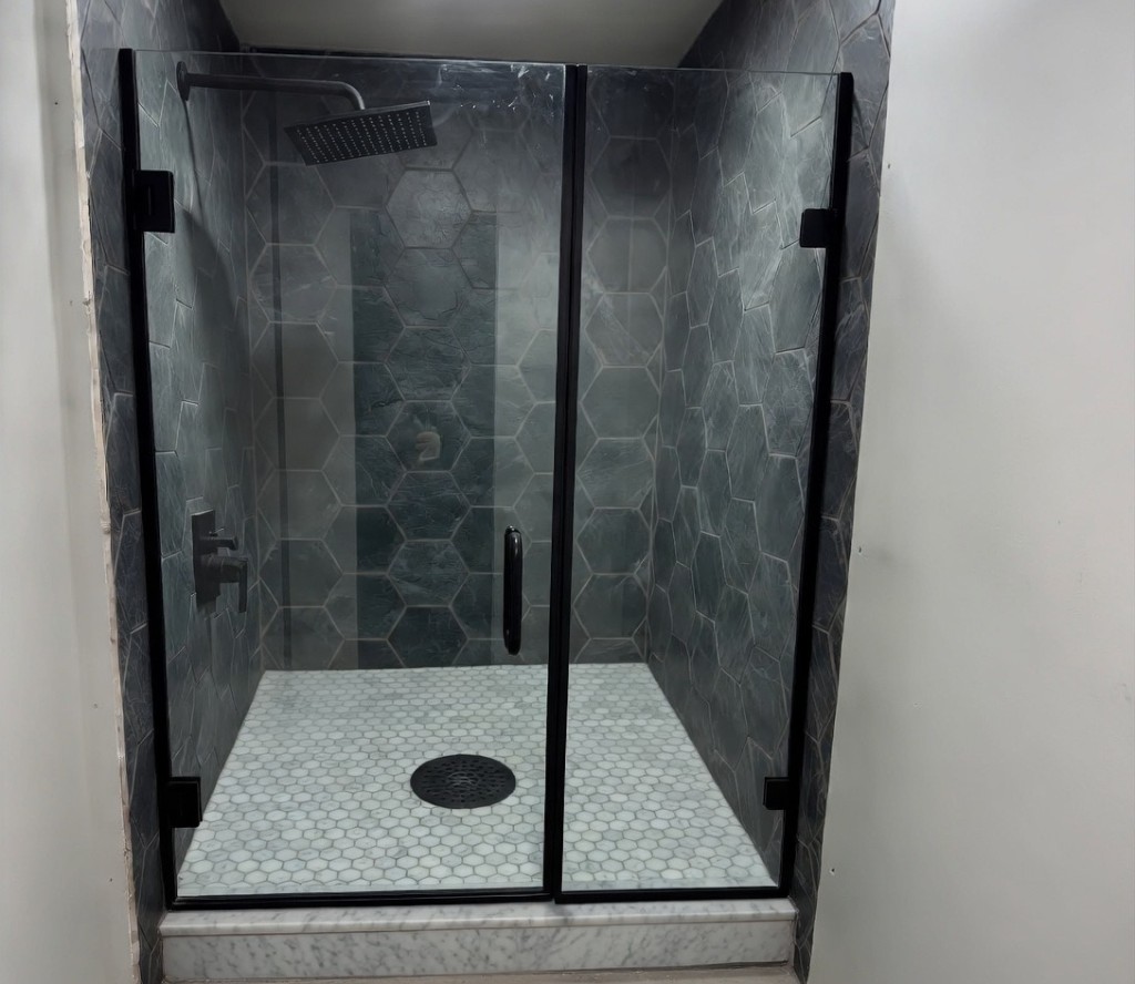 Design render — walk-in shower with charcoal hex wall tile, white hex floor tile, matte black fixtures