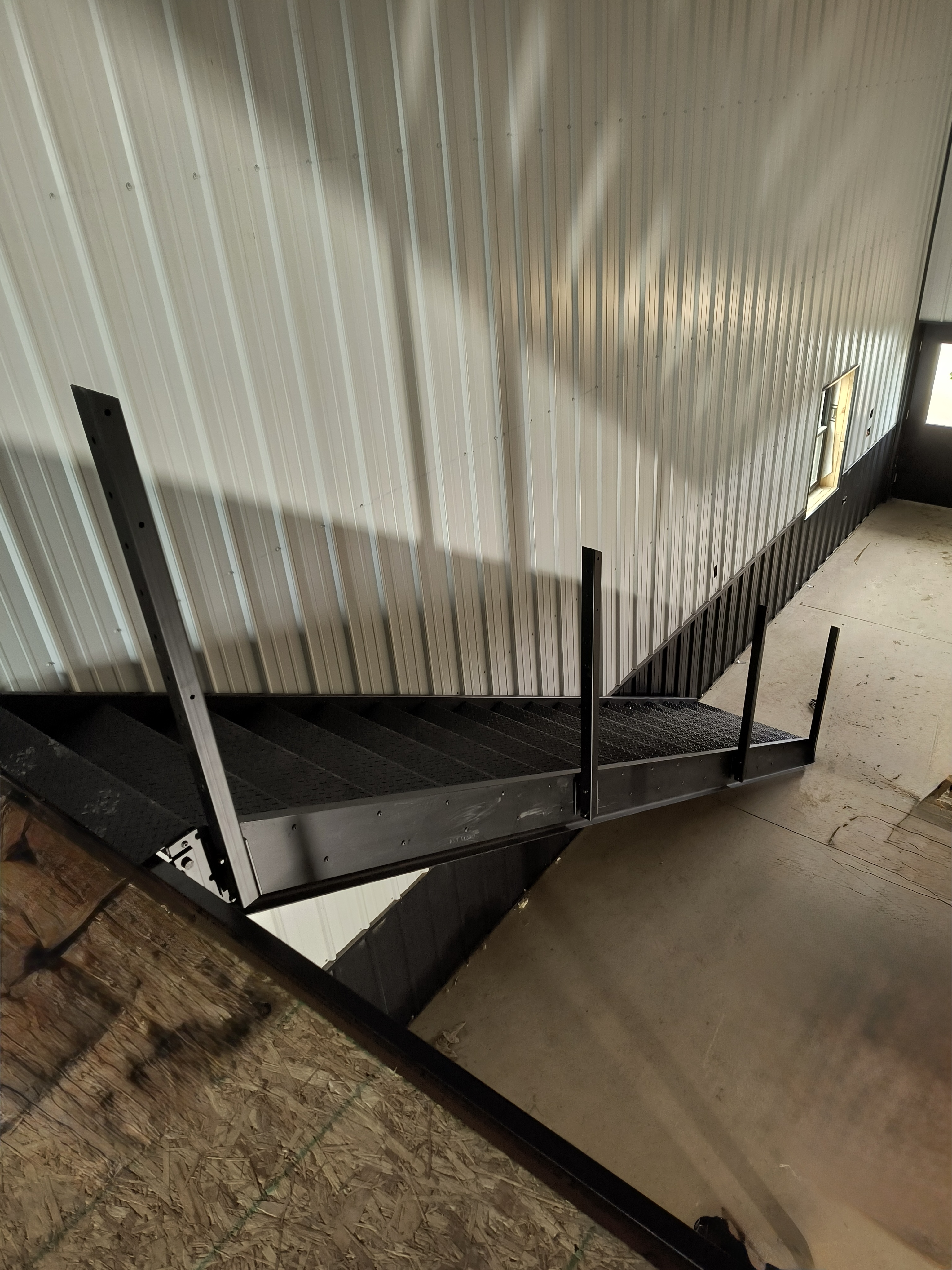 Stair landing connecting to the mezzanine — steel railing posts and expanded metal deck