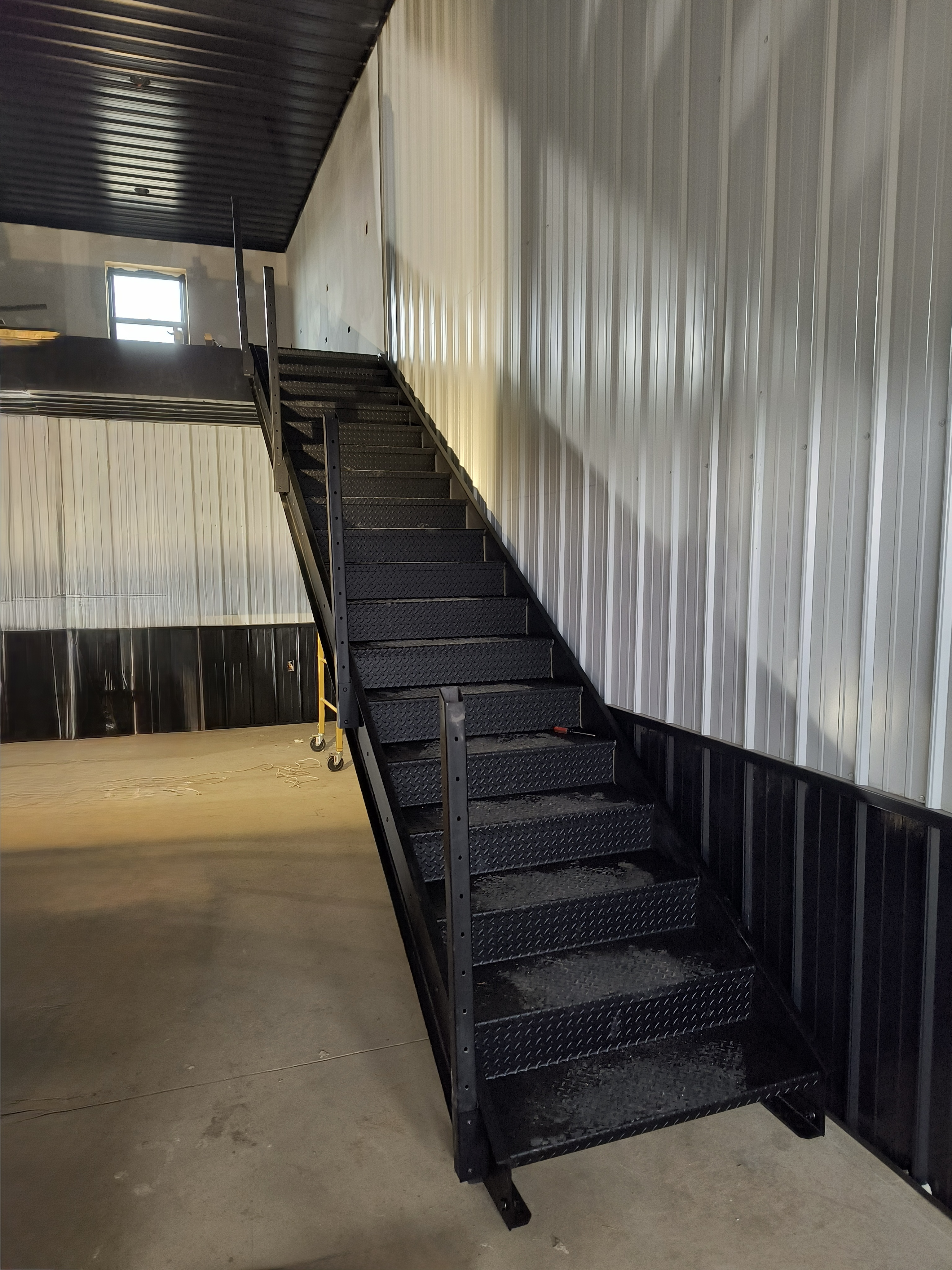 Full staircase view showing the mezzanine edge and black ceiling above