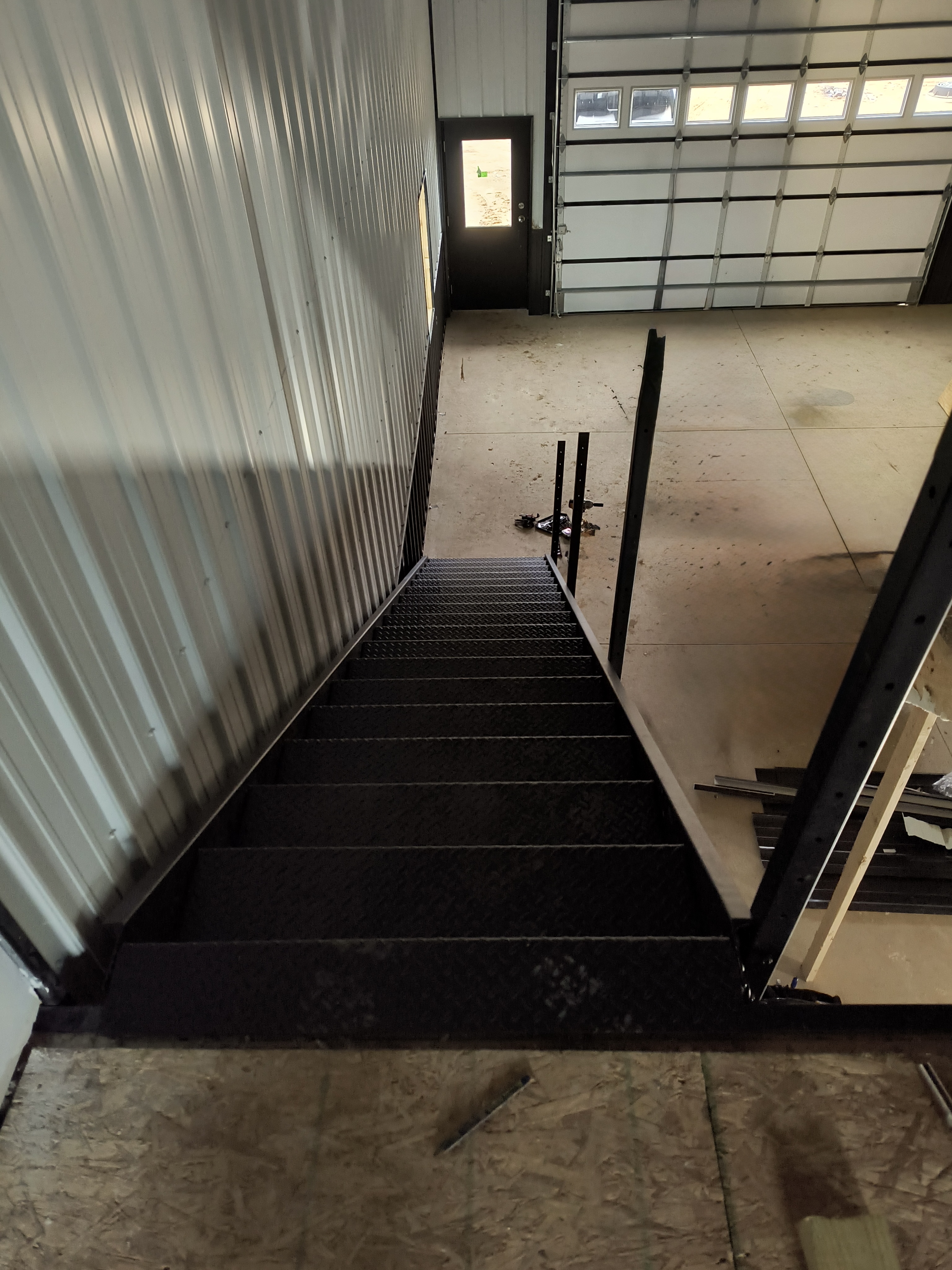 View from the mezzanine looking down — concrete floor, entry door, and 14x14 garage door