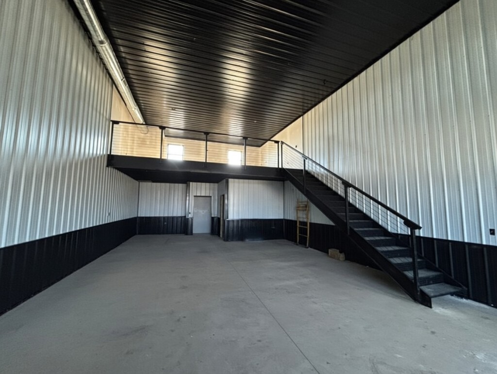 Building 1 Unit 1 interior — open main floor with black steel stairs, mezzanine, cable railings, and black ceiling