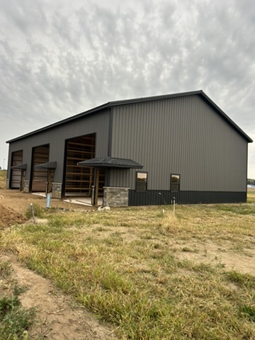 Three garage bays with stone wainscot and dark metal siding