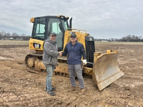 Partners on site in front of earth-moving equipment